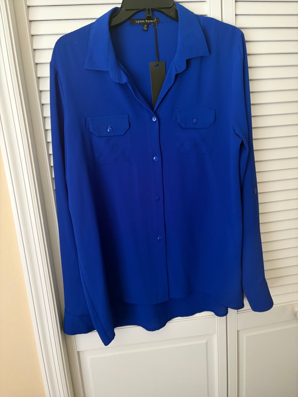 NWT button down blouse w/long sleeves & 2 front pockets. Back longer than front.